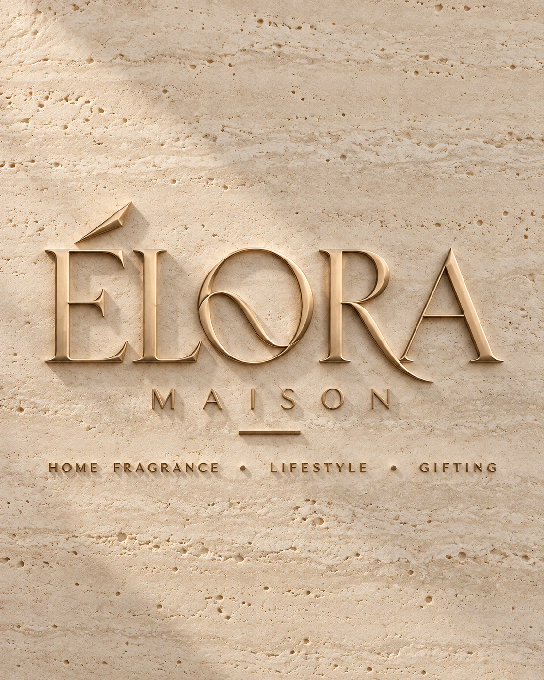 Logótipo original ÉLORA MAISON, dourado em relevo sobre pedra clara.